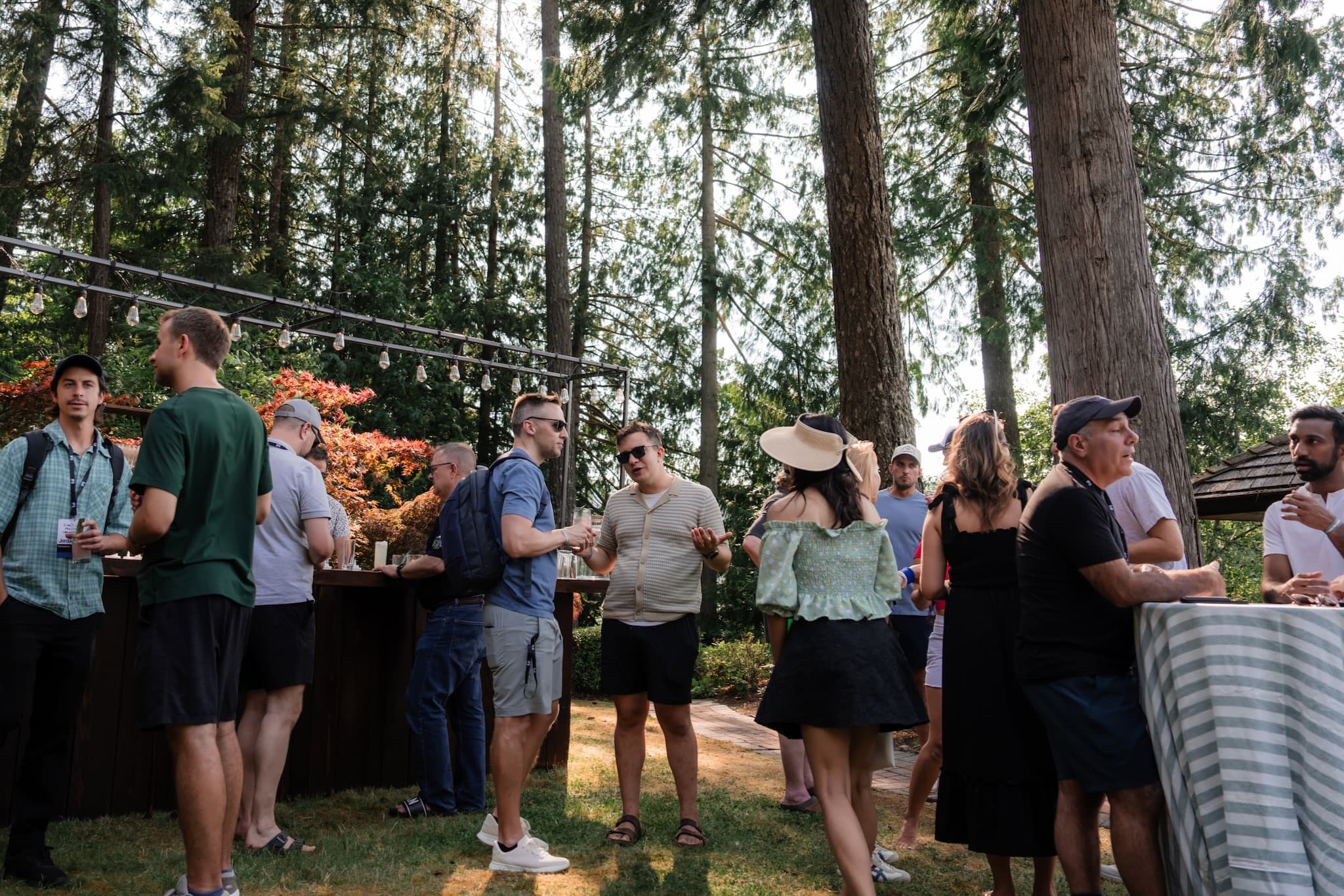 Attendees gathered lakeside at golden hour with string lights at IP3